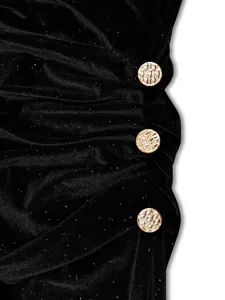 Black velvet dress detail featuring shimmering glitter and chic gold decorative buttons.