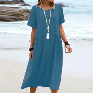 Detail shot of casual blue cotton linen midi dress with short sleeves on beach scenery.