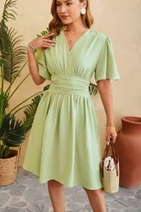Detail view of the light green V-neck dress, featuring gathered waist and flared sleeves.