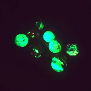Close up detail of glowing galaxy glass cabochons showing luminous green starry effects.
