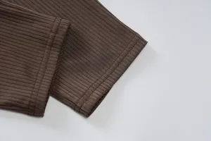 Detailed view of brown ribbed knit fabric showing fine texture and clean stitching work.