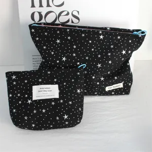 Detail view of black canvas makeup pouch with silver star sequins and brand woven tag.