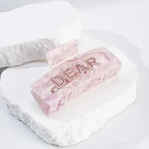 Elegante molletta per capelli in acetato rosa marrmorato con lettere DEAR in strass luminosi.