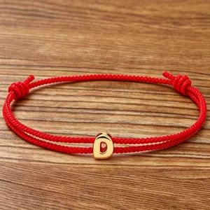 Red braided rope bracelet with a gold letter D charm, lucky couple wrist jewelry.