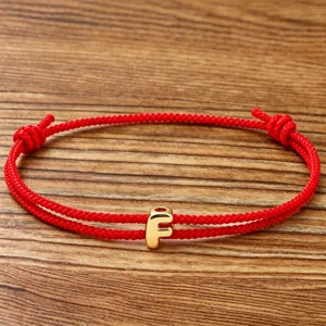 Red braided rope bracelet featuring gold letter F charm, adjustable minimalist couple jewelry.