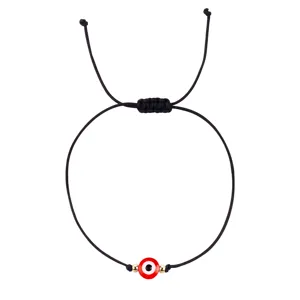 Détail de bracelet tressé mauvais œil rouge gros plan, charme cordon noir réglable.