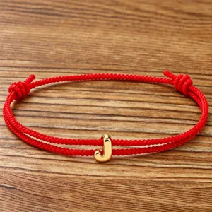 Red rope alphabet bracelet with gold letter charm, lucky braided jewelry for men and women.