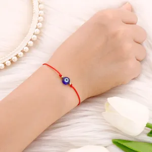 Gros plan détaillé du bracelet cordon rouge mauvais œil avec perle en verre bleu.