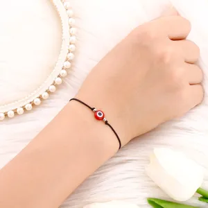 Gros plan détail d'un bracelet cordon rouge mauvais œil au poignet avec cadre de perles.