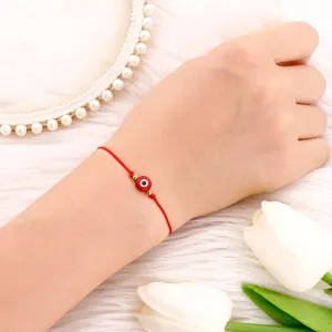Gros plan d'un bracelet cordon tissé rouge avec perle œil maléfique sur fond peluche.