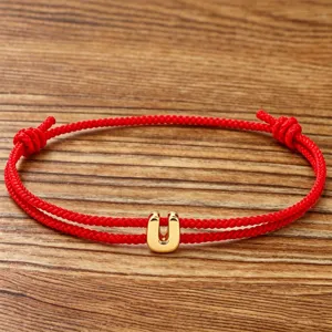 Red cord bracelet featuring a gold letter U pendant, perfect for daily wear or gifting.