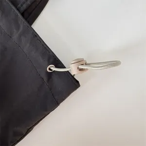 Primo piano del dettaglio coulisse della borsa tote in tela nera con occhiello metallico e fermo.