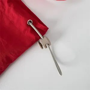 Detalle de bolso de hombro con cordón rojo que muestra ojal metálico y tope de diseño.