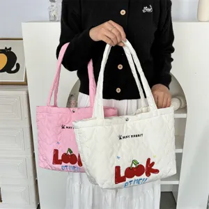 Detailed view of cute quilted heart tote bag with cherry embroidery and shoulder straps.