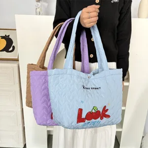 Quilted tote bag detail showing soft heart pattern fabric and cute cherry embroidery.