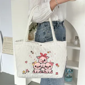 Close-up detailopname van de gewatteerde tote bag met schattige geborduurde varkens.