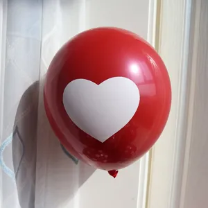 Close-up detail of a red latex balloon featuring a printed white heart decoration