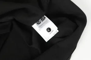 Close-up detail of the inner brand wash care label and size tag on a black cotton T-shirt
