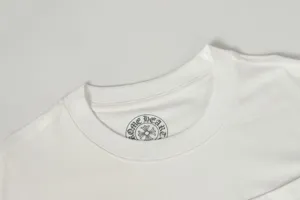 Close-up of a white crewneck t-shirt neckline showing a black circle graphic brand print inside.
