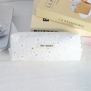 Detailopname van een wit canvas etui met zilveren sterren en een geweven label.