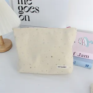 Detailed view of beige cosmetic bag with silver glitter stars, portable makeup storage pouch.