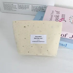 Close-up view of beige cosmetic pouch with silver stars, portable makeup bag for daily essentials.