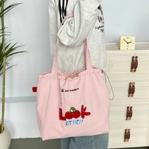 Bolso tote de lona rosa con bonito bordado de cerezas y cierre de cordón práctico para uso diario.