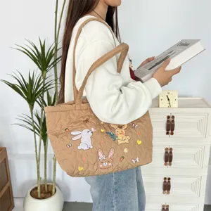 Gedetailleerd overzicht van de gewatteerde shopper met leuke geborduurde konijnen en ruimte.