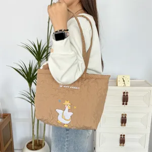 Gedetailleerd overzicht van gewatteerde kaki shopper met hartjespatroon en geborduurde eend.
