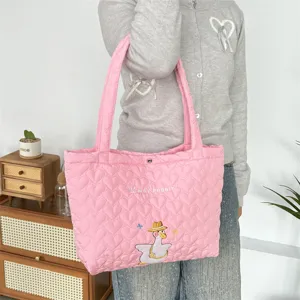 Close-up detail of pink quilted tote bag with cute embroidery, soft shoulder bag design.