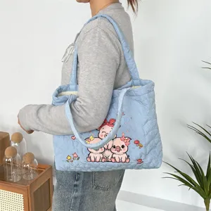 Close-up detail of the light blue quilted tote bag showcasing cute cartoon pig embroidery.