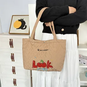 Quilted tote bag detail showcasing cute cherry embroidery and soft heart pattern fabric surface.