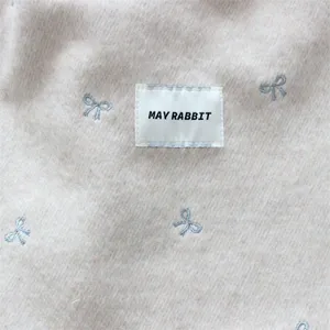 Detailopname van gestructureerde stoffen tas met schattige strik en merklabel.
