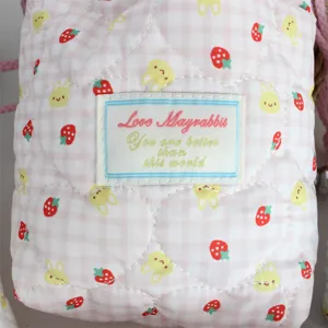 Close-up detail of pink gingham quilted padded drawstring storage bag with cute print.