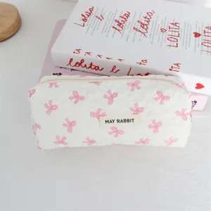 Primo piano di un astuccio trapuntato bianco con fiocchi rosa e una graziosa etichetta.