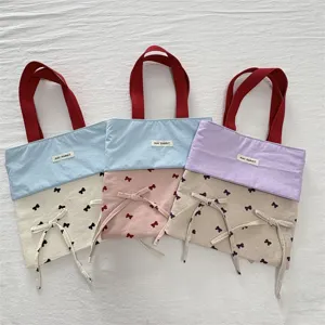 Detailansicht der Canvas-Tasche mit süßer Schleifendeko, Farbblock-Design und stabilen roten Henkeln.