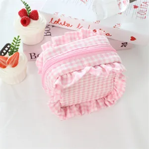 Dettaglio trousse trucco a quadri rosa, mini borsetta carina con volant e chiusura a zip.