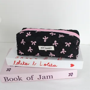 Primo piano di astuccio trapuntato nero con fiocchi rosa ed etichetta su libri decorativi.