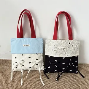 Nahaufnahme der Segeltuchtasche mit roten Griffen, süßen Schleifenknoten und feinen Nähten.