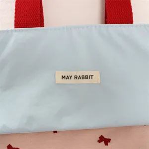 Detailansicht der Segeltuch-Handtasche mit Farbkombination, roten Griffen und Schleifen.