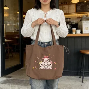 Vista detallada de un bolso tote de lona marrón con diseño bordado de cerdito tierno.