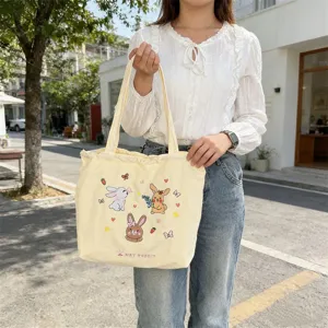Vista dettagliata di una borsa tote in tela ricamata con coniglietto, ideale per l'uso quotidiano.