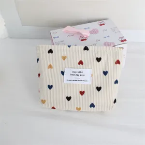 Detail view of the cute corduroy cosmetic bag with colorful heart prints and a woven label.