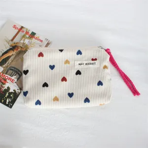 Corduroy cosmetic pouch with colorful heart print, zipper closure and handy wrist strap.