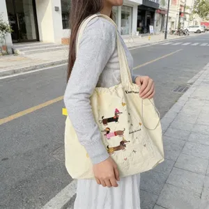 Dettaglio di una borsa shopper beige con coulisse e ricamo di bassotto carino per donna.