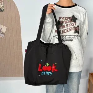 Elegante bolso de lona negro con bonito bordado de cerezas y cierre de cordón ajustable.