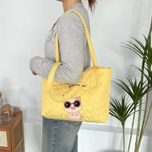 Detail view of the cute yellow quilted tote bag with pig embroidery and heart pattern for daily use.