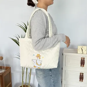 Gedetailleerd overzicht van de gewatteerde canvas tote tas met schattige eend-borduurwerk.