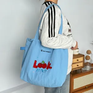 Bolso tote de lona azul con bonito bordado de cerezas y cordón ajustable para cierre.