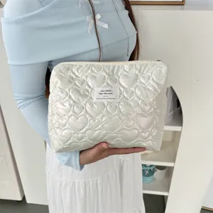 Detailed shot of quilted heart pattern PU cosmetic pouch, soft texture and portable design.